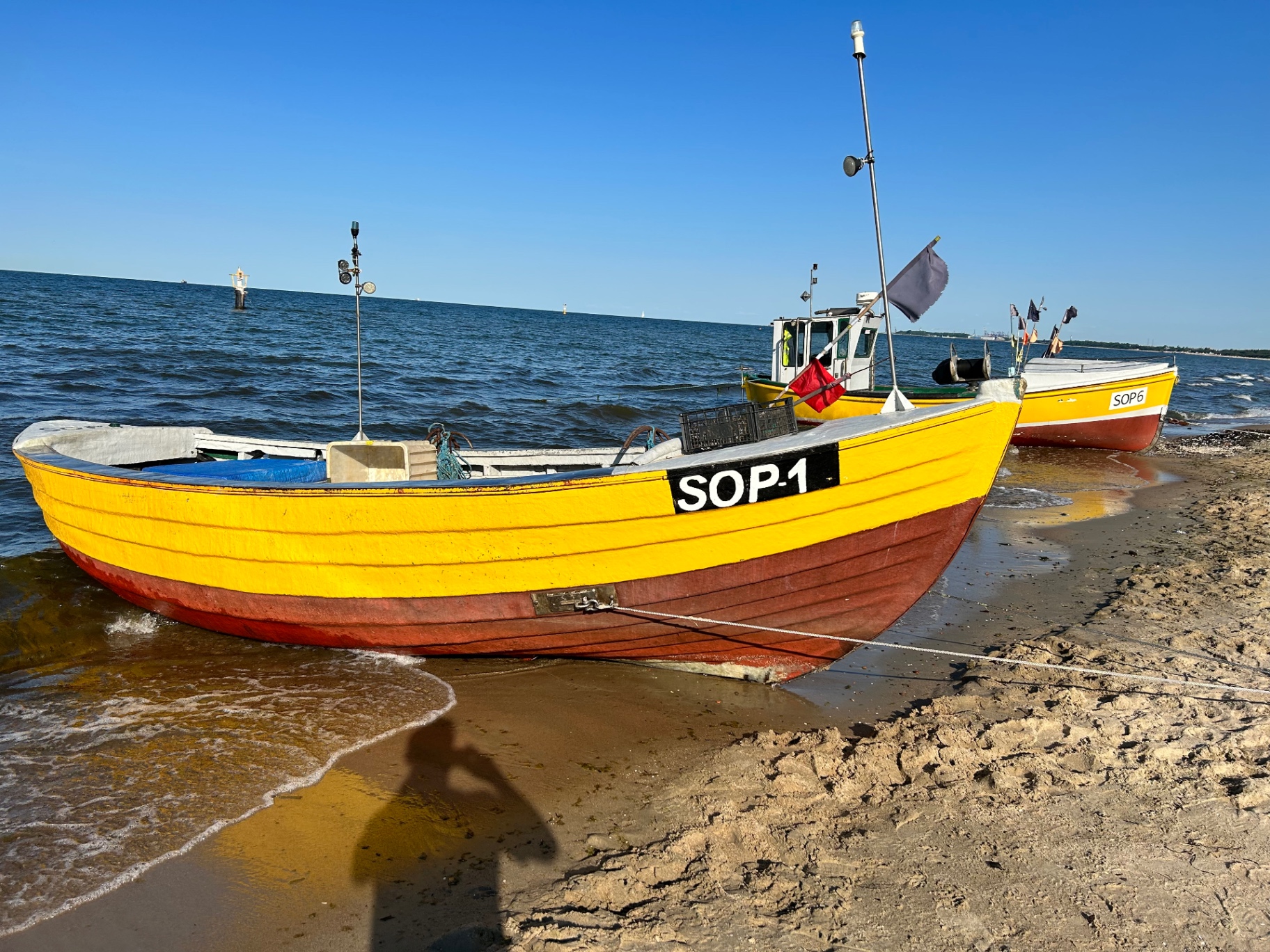 Kolorowe tradycyjne łodzie rybackie na plaży w Sopocie - kultowe żółte i czerwone drewniane łodzie na tle błękitnego Bałtyku