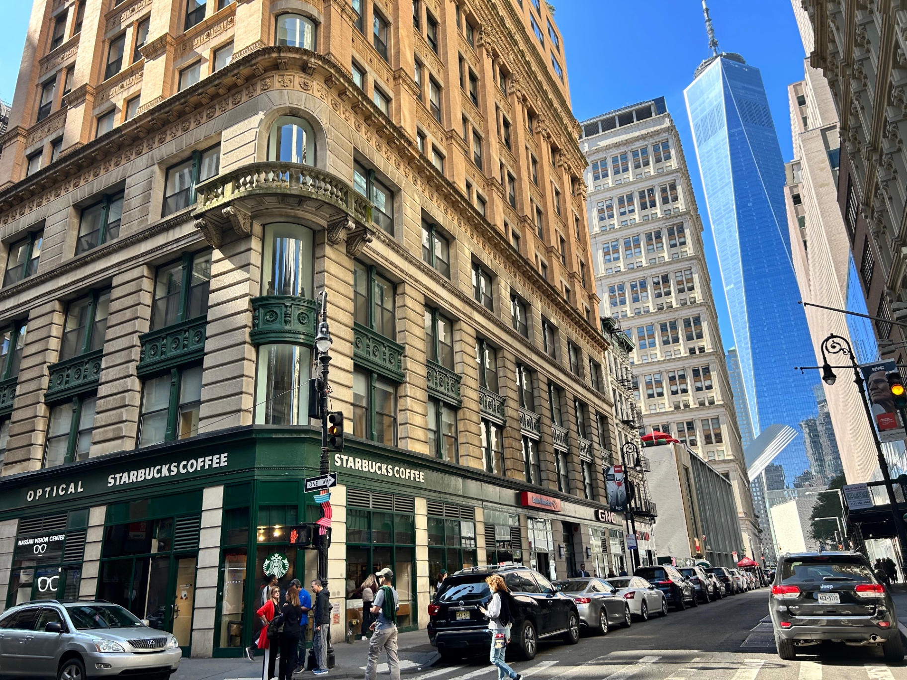 Róg ulicy na Dolnym Manhattanie z górującym w tle One World Trade Center - klasyczna architektura Nowego Jorku spotyka nowoczesną panoramę