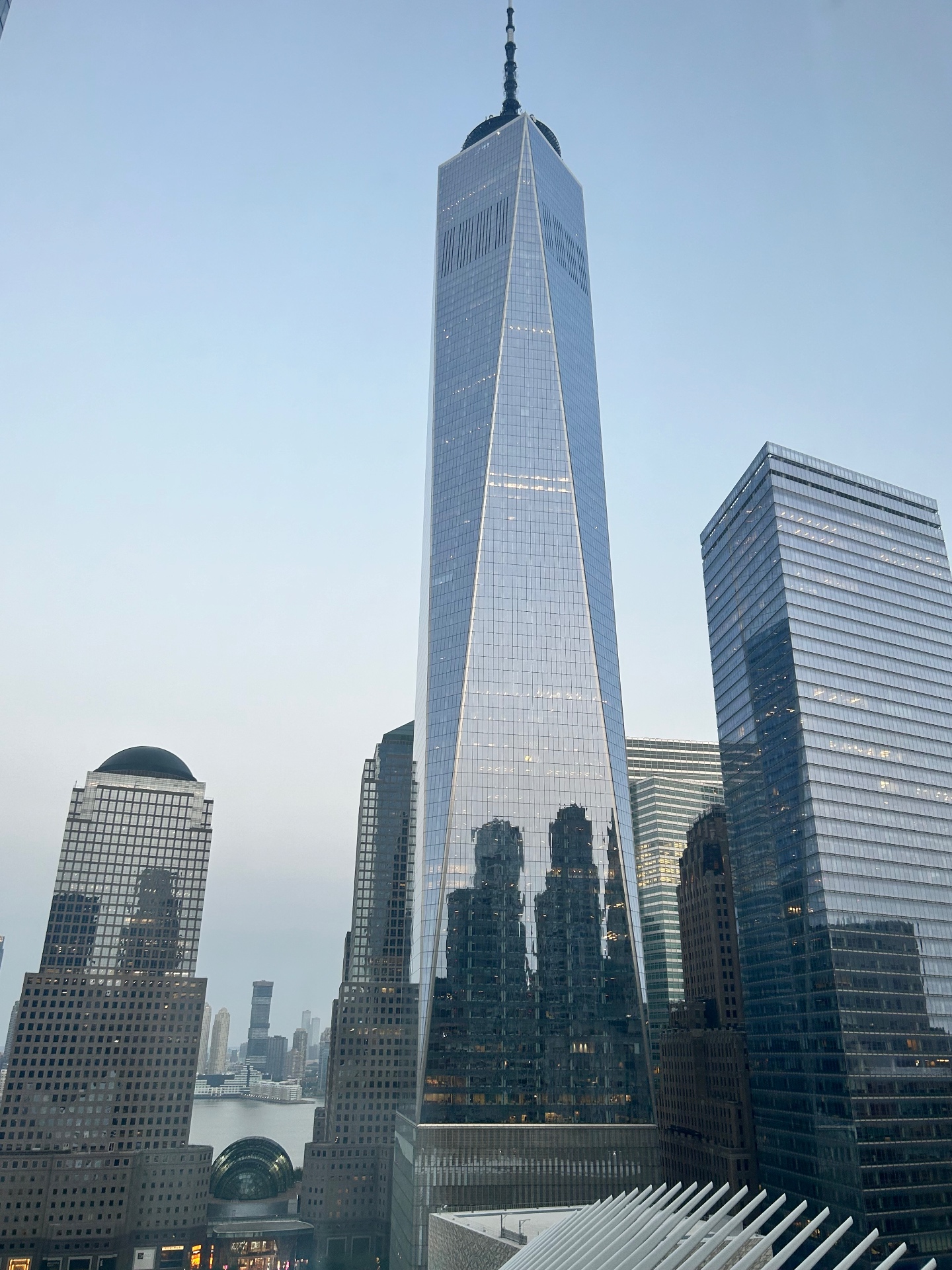 One World Trade Center górujące nad Dzielnicą Finansową - odbicia panoramy miasta na szklanej fasadzie o zmierzchu