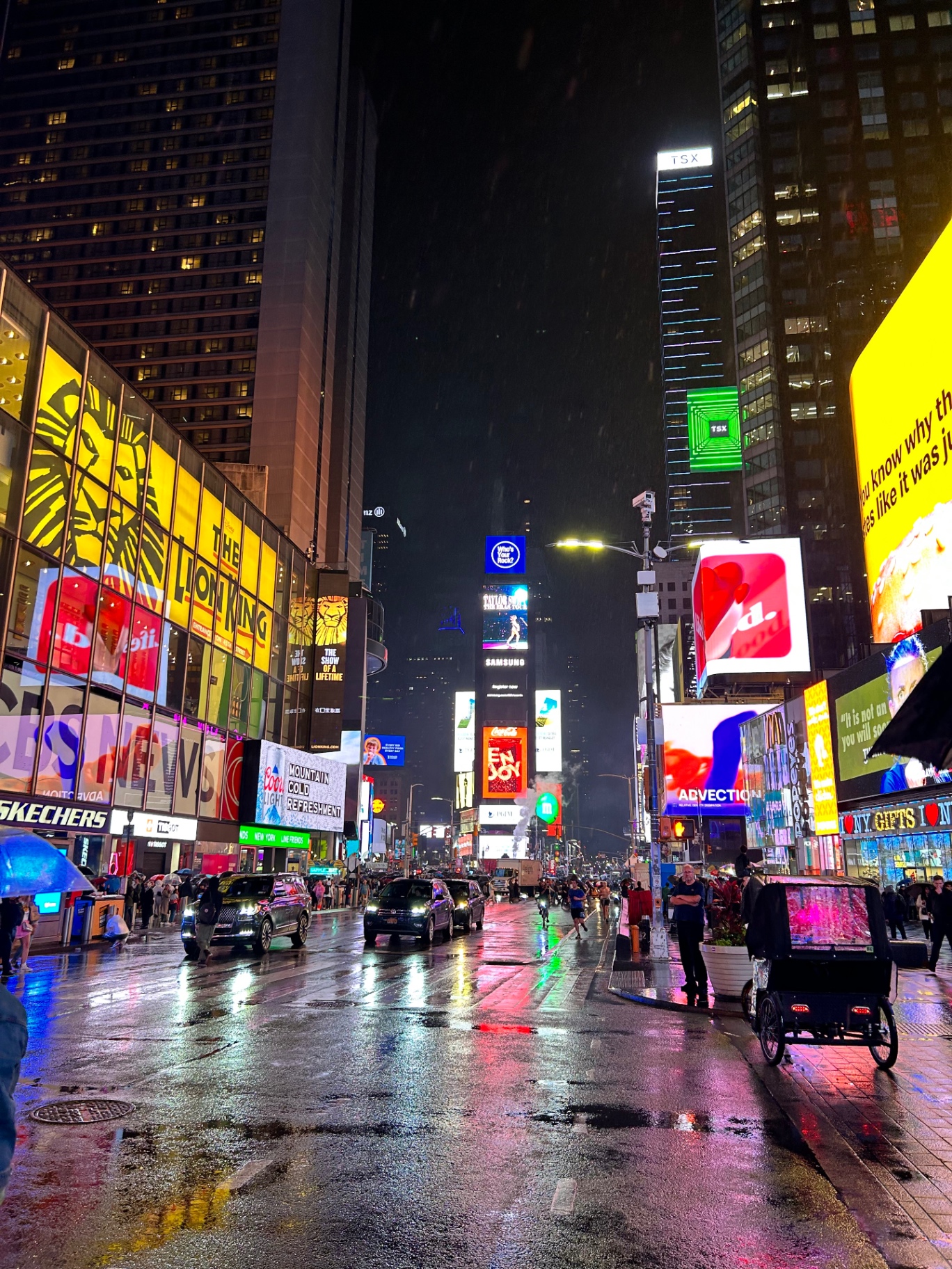Times Square w deszczową noc - neony odbijające się w mokrym chodniku tworzą magiczną atmosferę