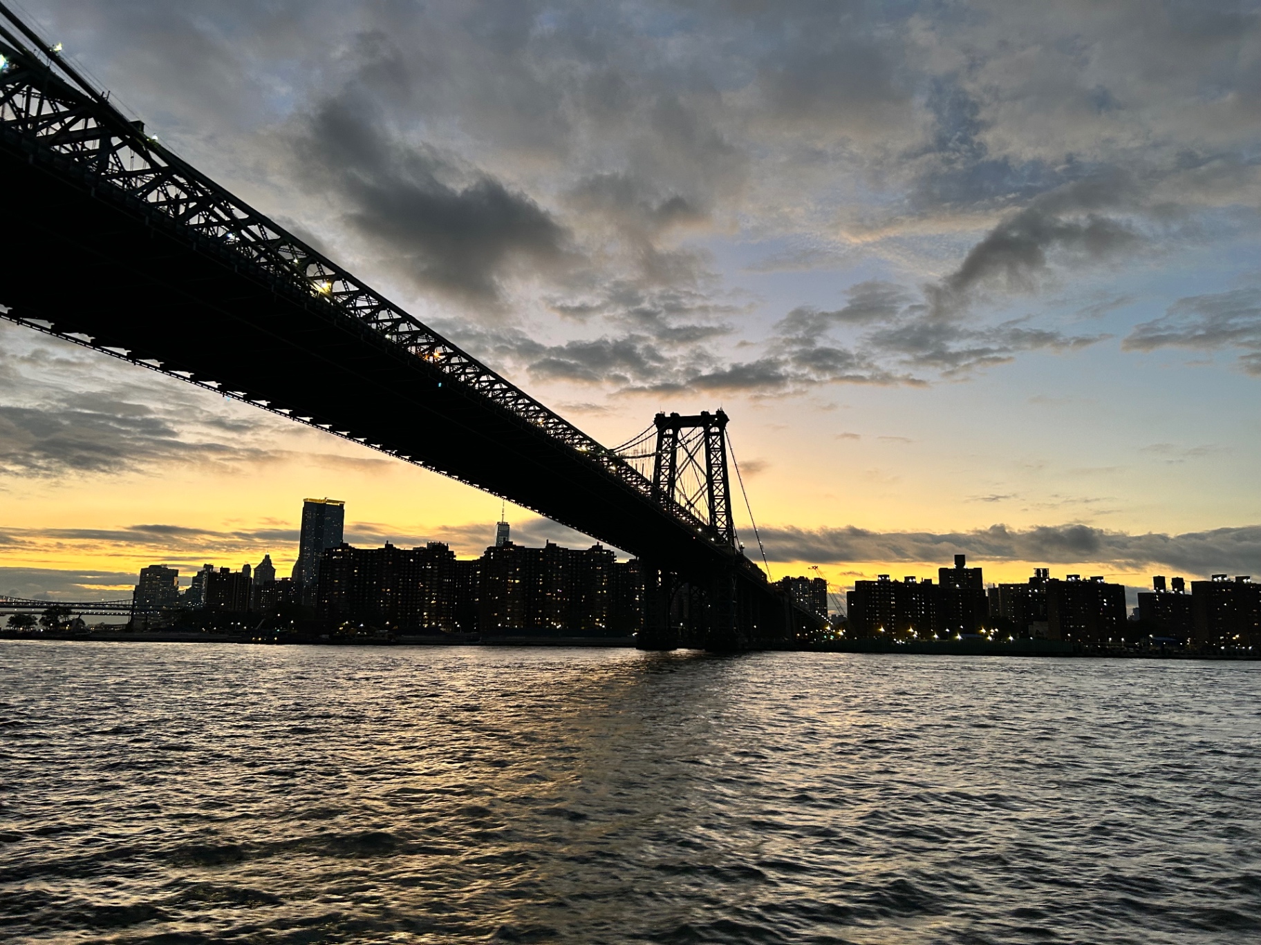 Most Williamsburg o zachodzie słońca - dramatyczna sylwetka na tle złotego nieba nad East River